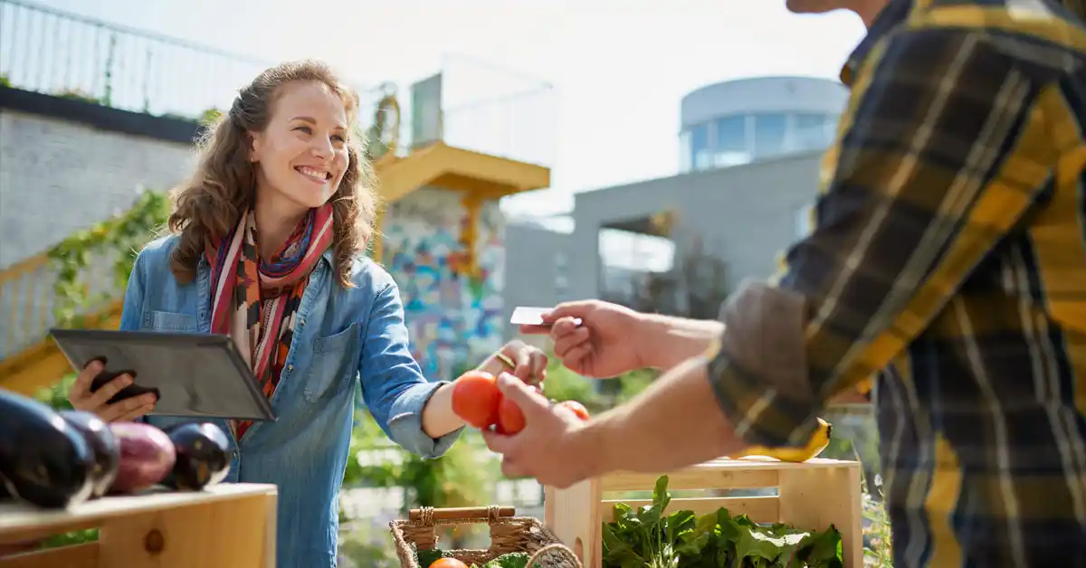 Smiling Woman Buying Tomatoes At A Farmer's Market